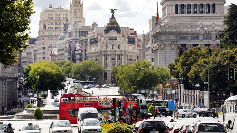 Ein roter Touristenbus an der Prachtstraße Gran Vía und Calle de Alcala in Madrid.