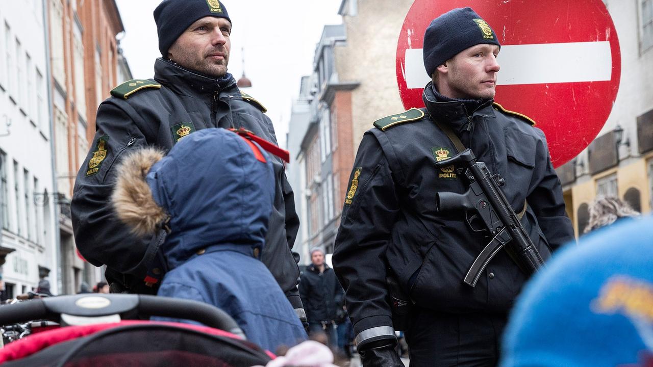 Kinder stehen vor zwei schwer bewaffneten Polizisten. Kinder stehen vor zwei schwer bewaffneten Polizisten.