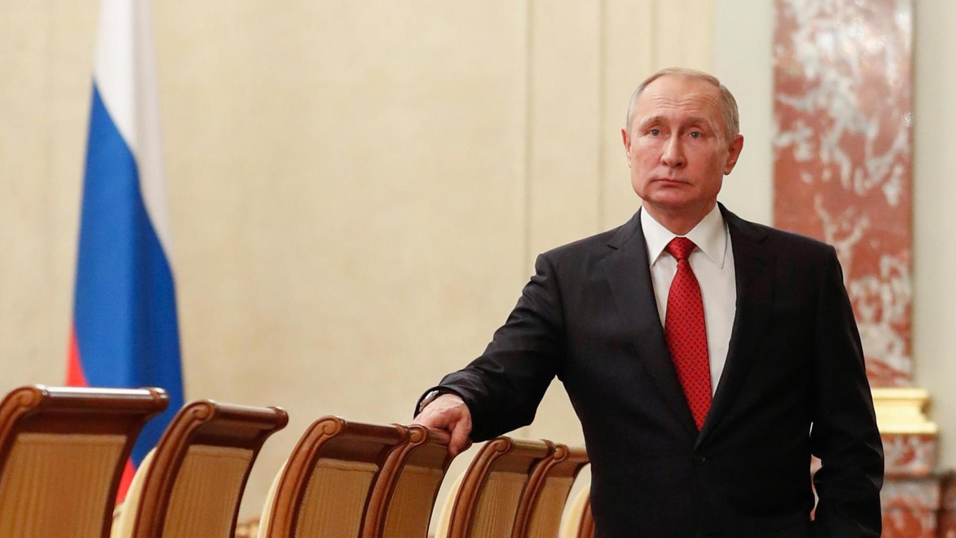 Russlands Präsident Wladimir Putin steht an einen Stuhl gelehnt im Kabinettsaal im Kremel.