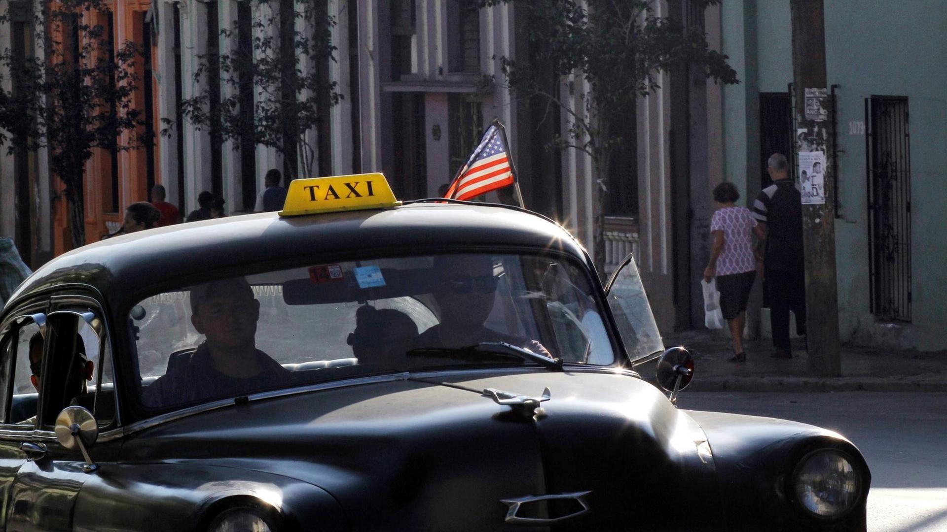 Ein altes kubanisches Taxi mit einer aufgesteckten USA-Fahne.