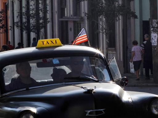 Ein altes kubanisches Taxi mit einer aufgesteckten USA-Fahne.