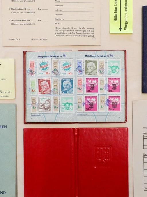 Ein Reisepass und andere Ausweisdokumente der DDR liegen auf einem Ausstellungstisch.