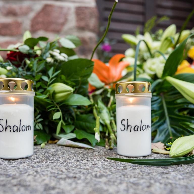 Blumen und Kerzen mit der Aufschrift Shalom vor der Synagoge in Halle.