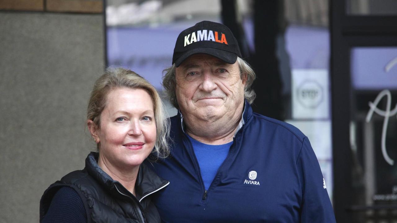 Der Regisseur John Kent Harrison hat eine Basecap, mit der Aufschrift "KAMALA", auf und steht neben einer weiblichen Begleitung (links).