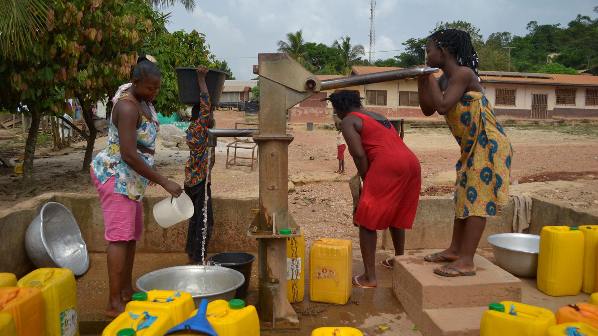 Frauen pumpen Wasser im ghanaischen Dorf Bonsaado Frauen pumpen Wasser im ghanaischen Dorf Bonsaado