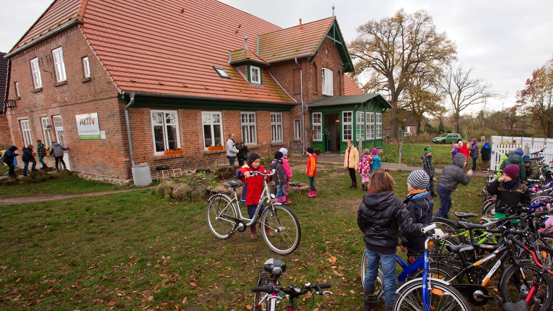 Schüler der privaten Grundschule in Bröbberow stellen auf der Wiese vor dem Schulgebäude ihre Fahrräder ab.