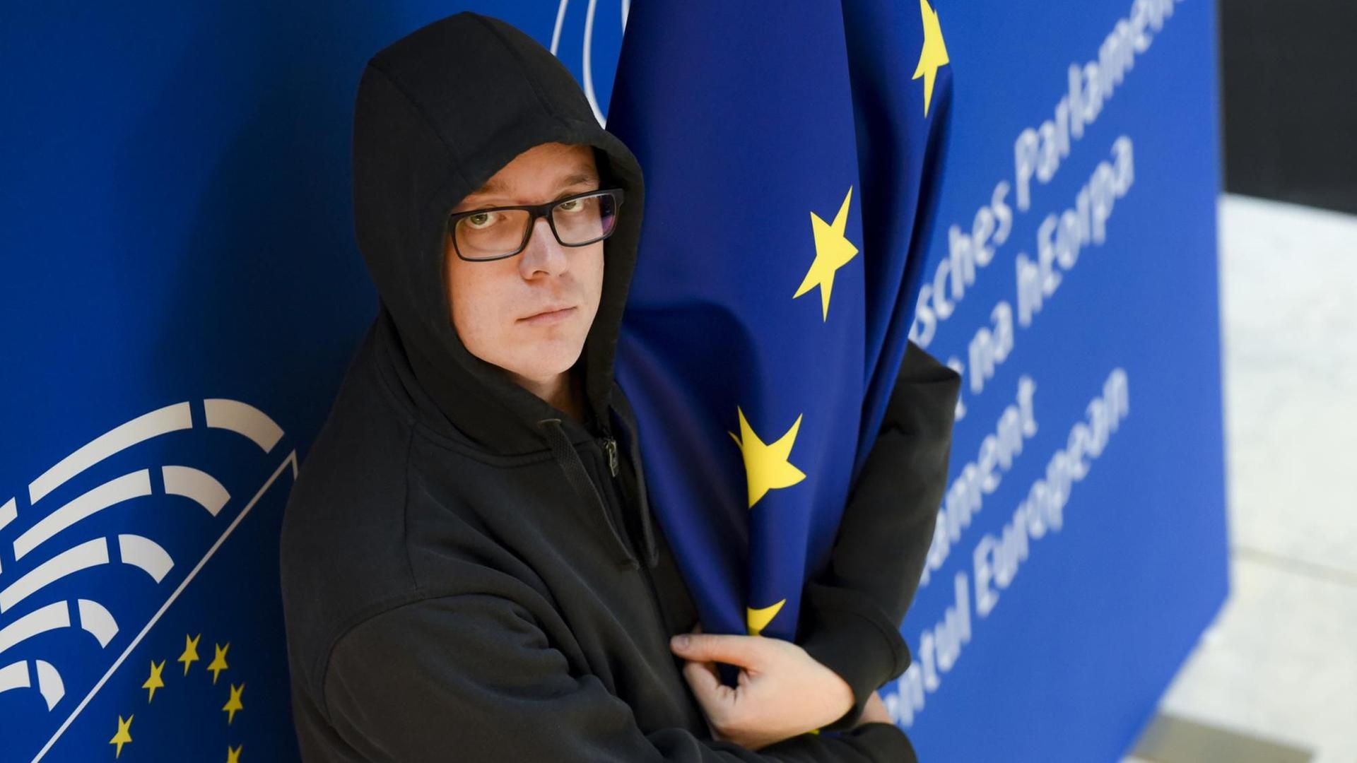 Der Satiriker und Politiker Nico Semsrott steht vor einer Wand im EU-Parlament