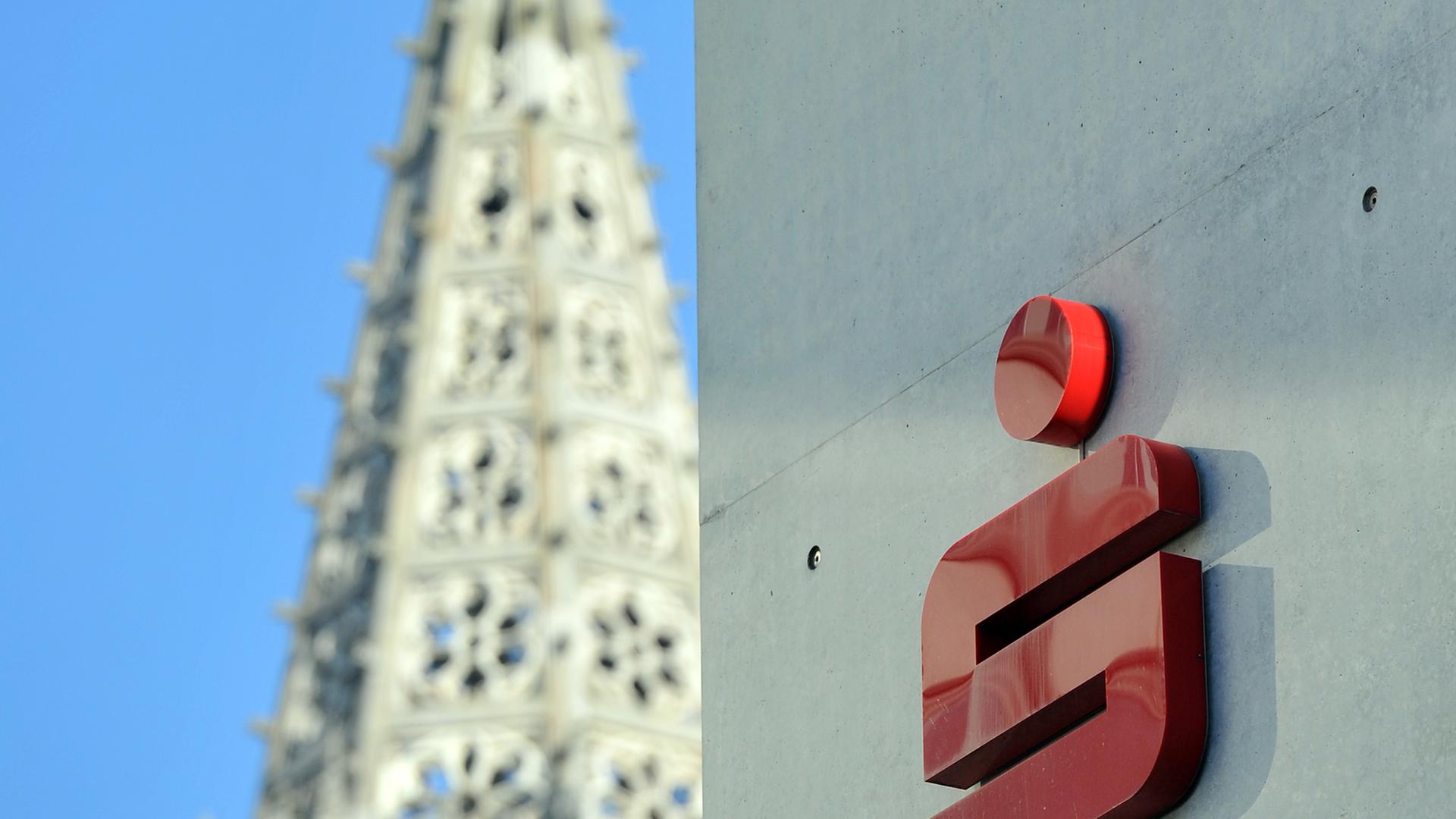 Das Logo der Sparkasse Ulm an einem Gebäude, im Hintergrund das Ulmer Münster. Das Logo der Sparkasse Ulm an einem Gebäude, im Hintergrund das Ulmer Münster.