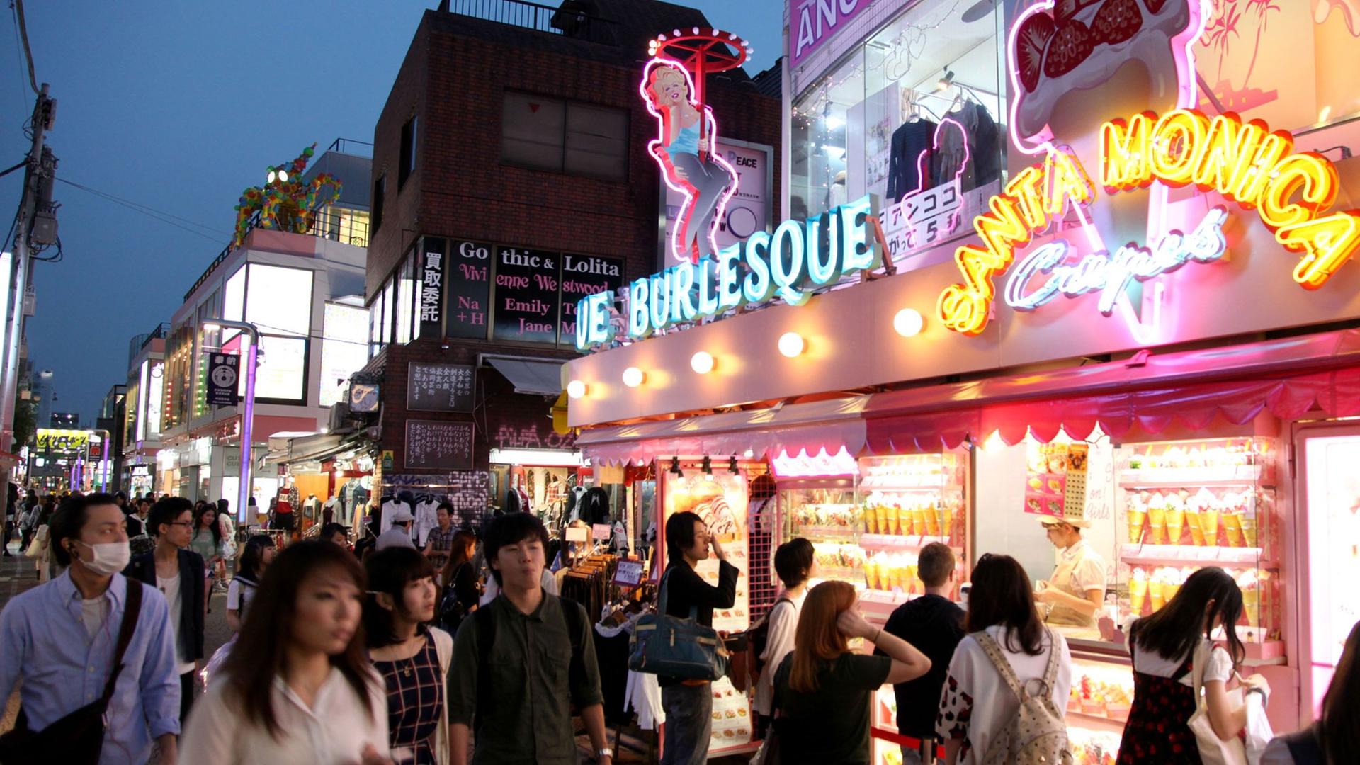 Passanten laufen durch eine Einkaufsstraße mit greller Leuchtreklame an den Geschäften in der japanischen Hauptstadt Tokio. Passanten laufen durch eine Einkaufsstraße mit greller Leuchtreklame an den Geschäften in der japanischen Hauptstadt Tokio.
