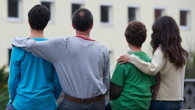 Eine Familie sitzt vor einem Asylwohnheim der Zentralen Ausländerbehörde des Landes Brandenburg in Eisenhüttenstadt.