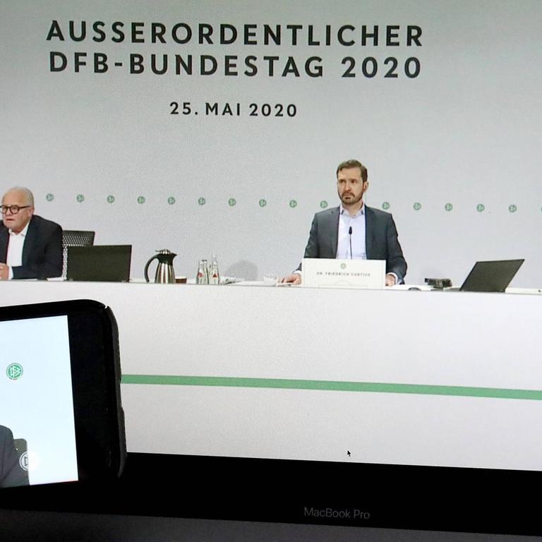 Beim DFB-Bundestag am 25.05.2020: Der 98. DFB-Bundestag wurde erstmals virtuell durchgefuehrt, hier im Livestream sind Fritz Keller (DFB-Präsident, links), Dr. Friedrich Curtius (DFB-Generalsekretär, Mitte) und Dr. Rainer Koch (1. DFB-Vizepräsident, rechts) auf einem Laptop sowie einem Smartphone zu sehen. 