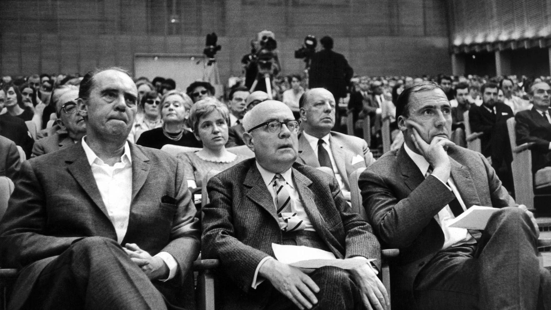 (L-r) Der Schriftsteller Heinrich Böll, der Soziologie-Professor Theodor Adorno und der Verleger Siegfried Unseld hören am 28.5.1968 bei einer Veranstaltung gegen die Notstandsgesetzgebung im Großen Sendesaal des Hessischen Rundfunks in Frankfurt am Main einem Vortrag zu. (L-r) Der Schriftsteller Heinrich Böll, der Soziologie-Professor Theodor Adorno und der Verleger Siegfried Unseld hören am 28.5.1968 bei einer Veranstaltung gegen die Notstandsgesetzgebung im Großen Sendesaal des Hessischen Rundfunks in Frankfurt am Main einem Vortrag zu.