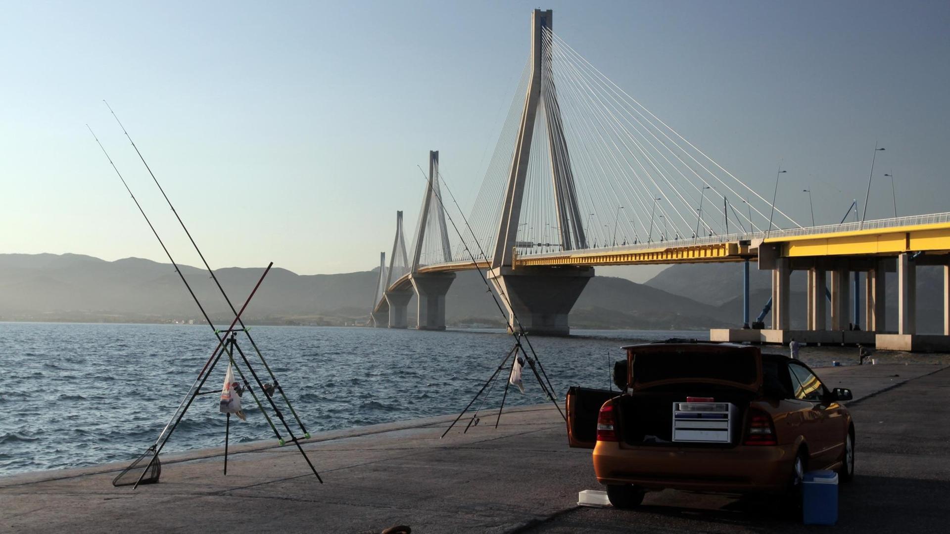 Angler warten im Auto nahe der Rio-Antirio-Brücke bei Patras in der Abenddämmerung auf einen Biss an ihren zahlreich aufgestellten Angeln Angler warten im Auto nahe der Rio-Antirio-Brücke bei Patras in der Abenddämmerung auf einen Biss an ihren zahlreich aufgestellten Angeln