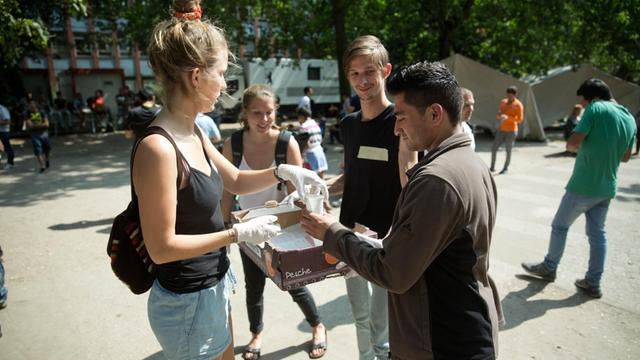 Ehrenamtliche der Initiative Moabit hilft versorgen Flüchtlinge mit Essen in Berlin.