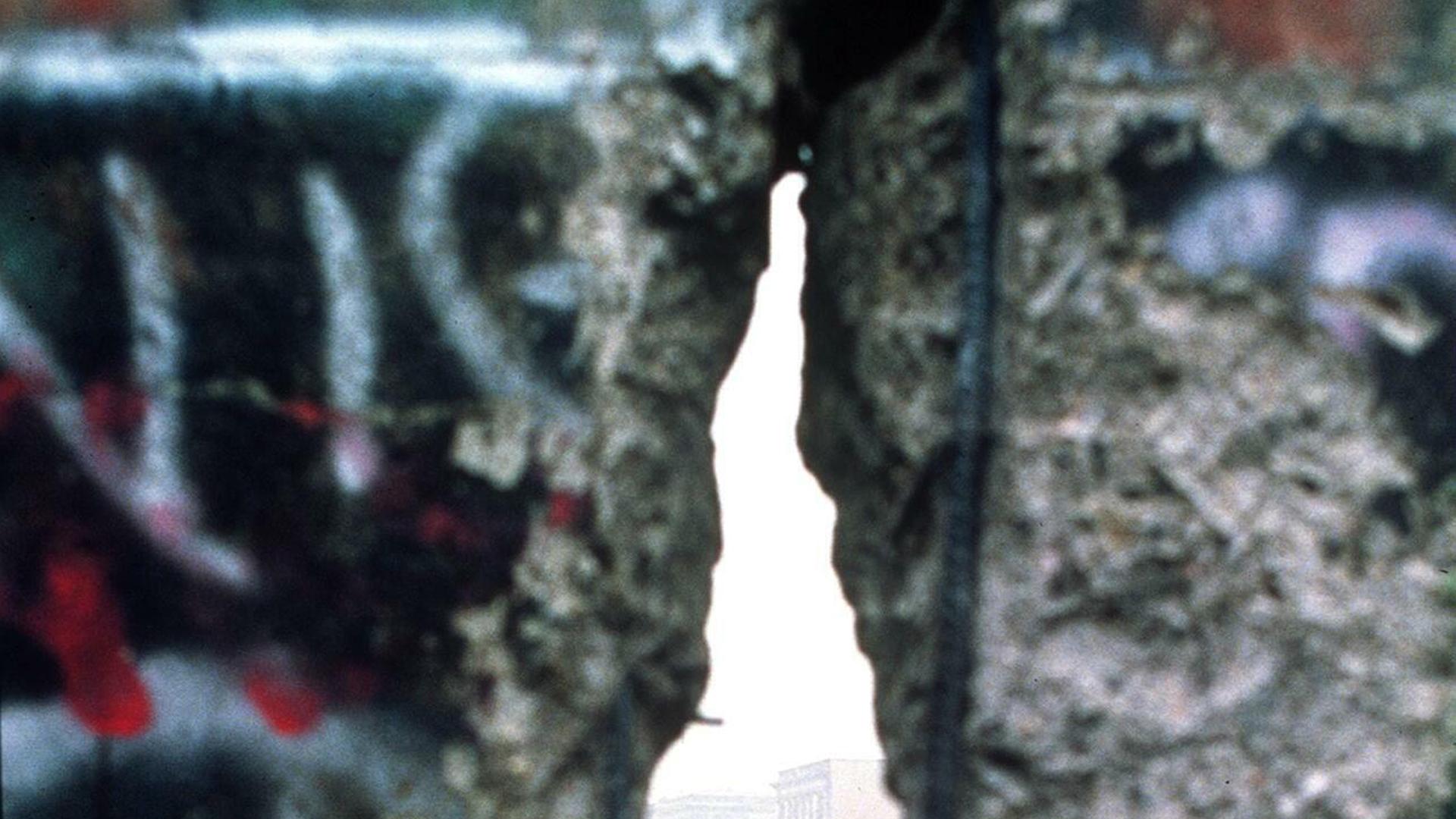 Zu sehen ist die Berliner Mauer, die ein Loch aufweist.