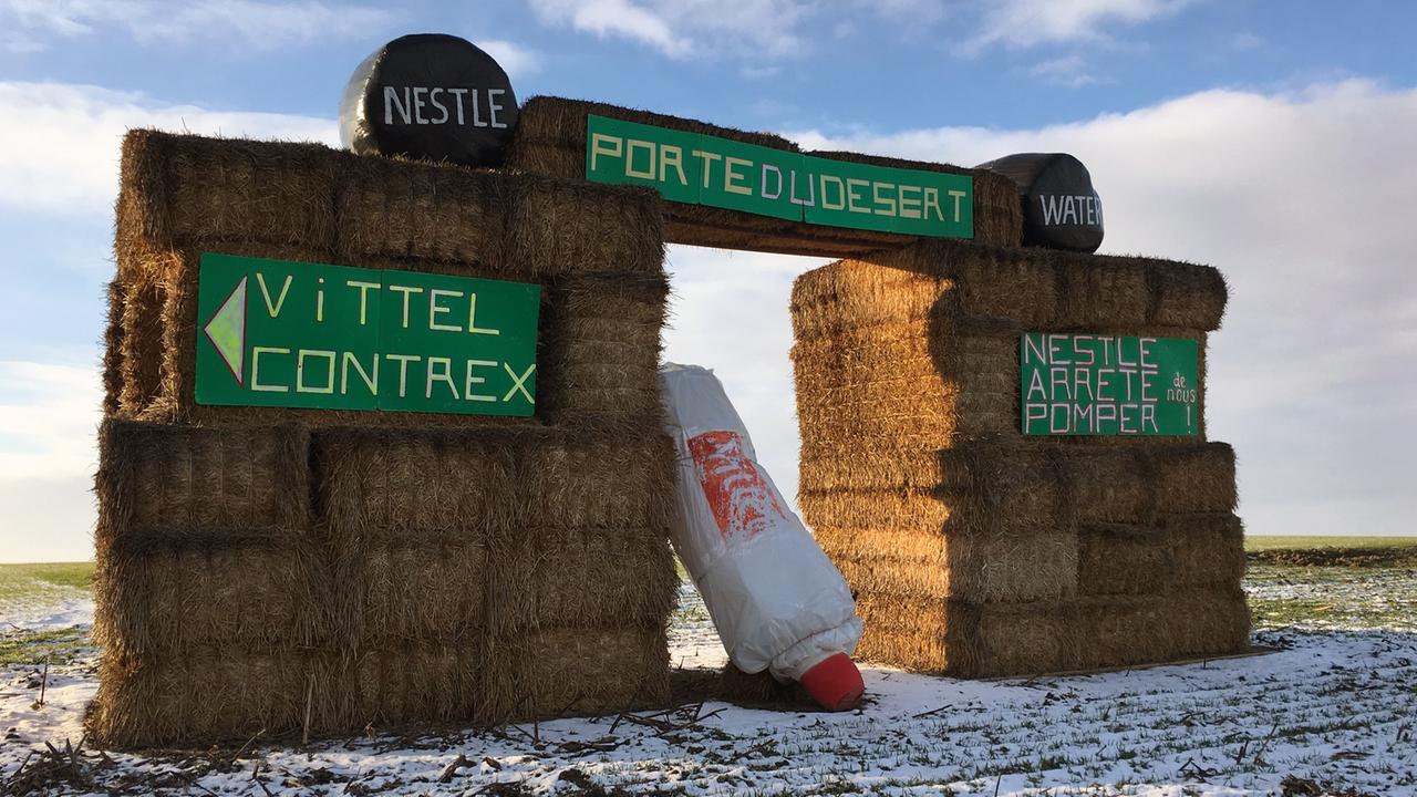 Eine Strohballenkonstruktion, die den Protest der Gemeinde Valfroicourt ausdrückt. „Porte du désert“ bedeutet „Tor zur Wüste“. Die Anwohner fordern Nestlé auf, nicht mehr ihr Trinkwasser abzupumpen. Sie fürchten negative Folgen für das Ökosystem. Eine Strohballenkonstruktion, die den Protest der Gemeinde Valfroicourt ausdrückt. „Porte du désert“ bedeutet „Tor zur Wüste“. Die Anwohner fordern Nestlé auf, nicht mehr ihr Trinkwasser abzupumpen. Sie fürchten negative Folgen für das Ökosystem.