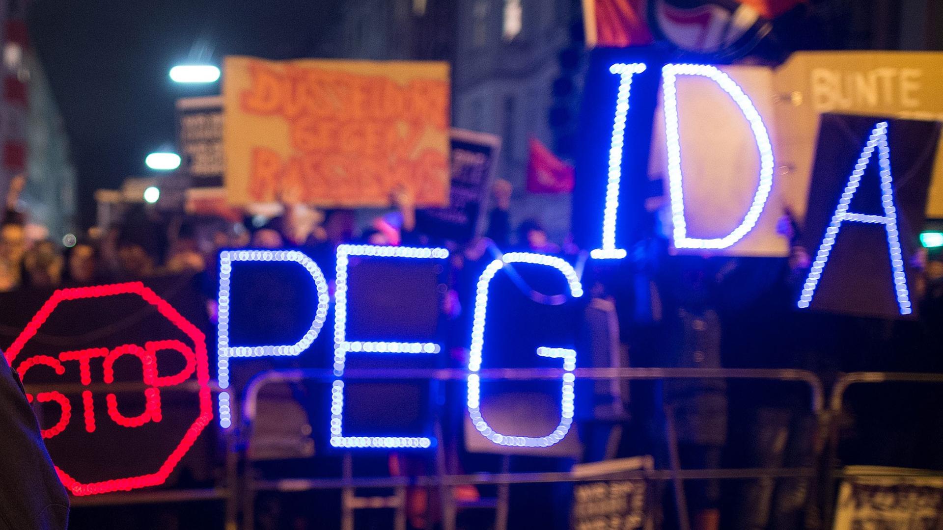 Gegner der Anti-Islam-Bewegung "Dügida" demonstrieren am 12.01.2015 in Düsseldorf (Nordrhein-Westfalen) mit einer Leuchtschrift "Stop PEGIDA" Gegner der Anti-Islam-Bewegung "Dügida" demonstrieren am 12.01.2015 in Düsseldorf (Nordrhein-Westfalen) mit einer Leuchtschrift "Stop PEGIDA"