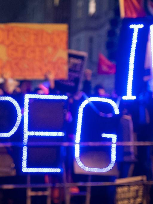 Gegner der Anti-Islam-Bewegung "Dügida" demonstrieren am 12.01.2015 in Düsseldorf (Nordrhein-Westfalen) mit einer Leuchtschrift "Stop PEGIDA"