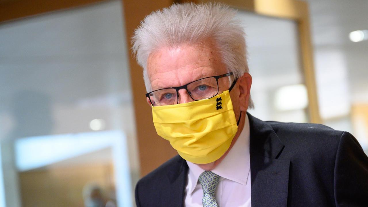 Kretschmann trägt eine leuchtend gelbe Mund- und Nasenbedeckung aus Stoff. Kretschmann trägt eine leuchtend gelbe Mund- und Nasenbedeckung aus Stoff.