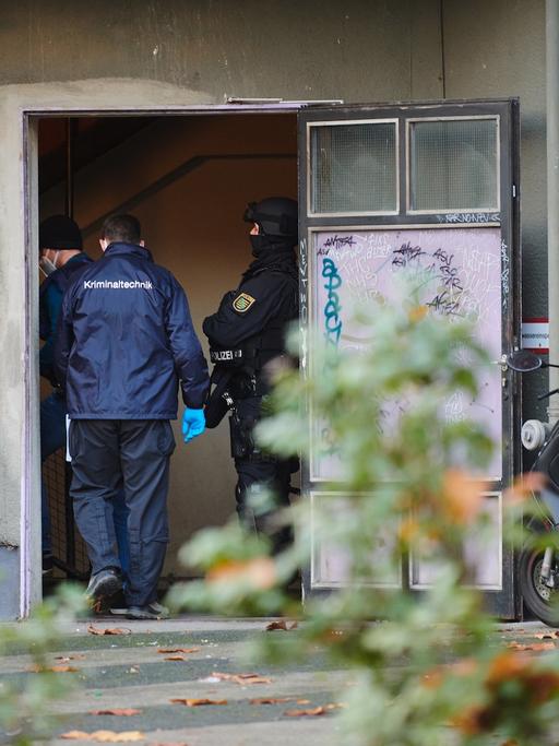 Polizei und Kriminaltechniker stehen bei einem Einsatz in einem Hauseingang. Knapp ein Jahr nach dem Kunstdiebstahl im Dresdner Grünen Gewölbe hat die Polizei am Dienstagmorgen in Berlin drei Tatverdächtige festgenommen. Seit dem Morgen wurden insgesamt 18 Objekte durchsucht.
