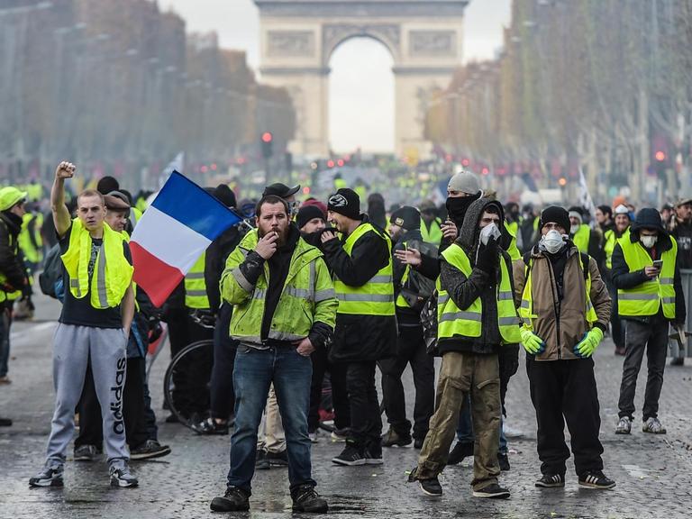 Hunderte Demonstranten mit gelben Westen auf der Straße. Im Hintergrund ist der Triumphbogen zu sehen.