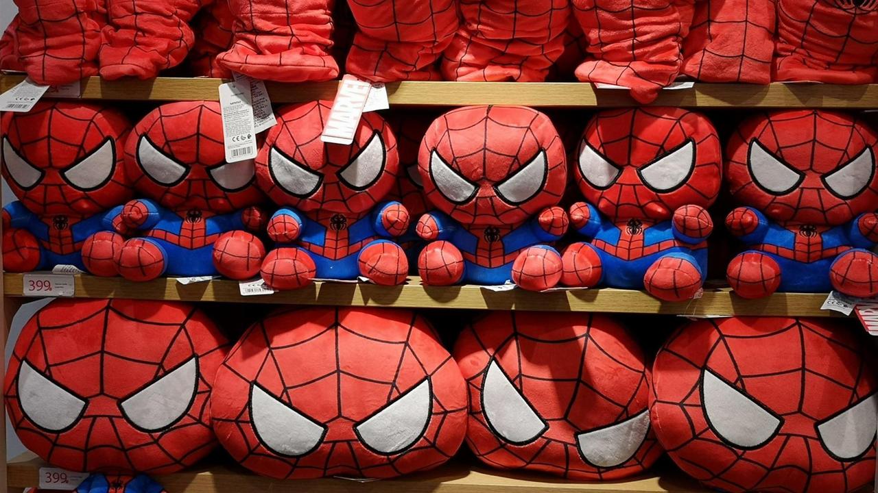 Superhelden von Marvel, Spiderman Kuscheltiere und Hüte stehen dicht gedrängt in einem Regal.