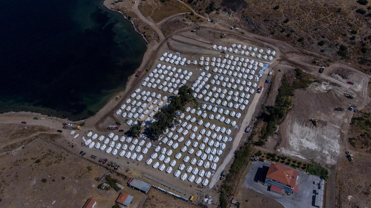 Luftaufnahme mit dem Blick auf eine Bucht mit vielen weissen UNHCR-Zelten in Kara Tepe, Lebos.
