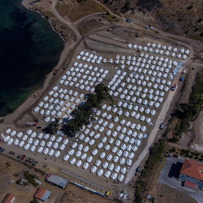 Luftaufnahme mit dem Blick auf eine Bucht mit vielen weissen UNHCR-Zelten in Kara Tepe, Lebos.
