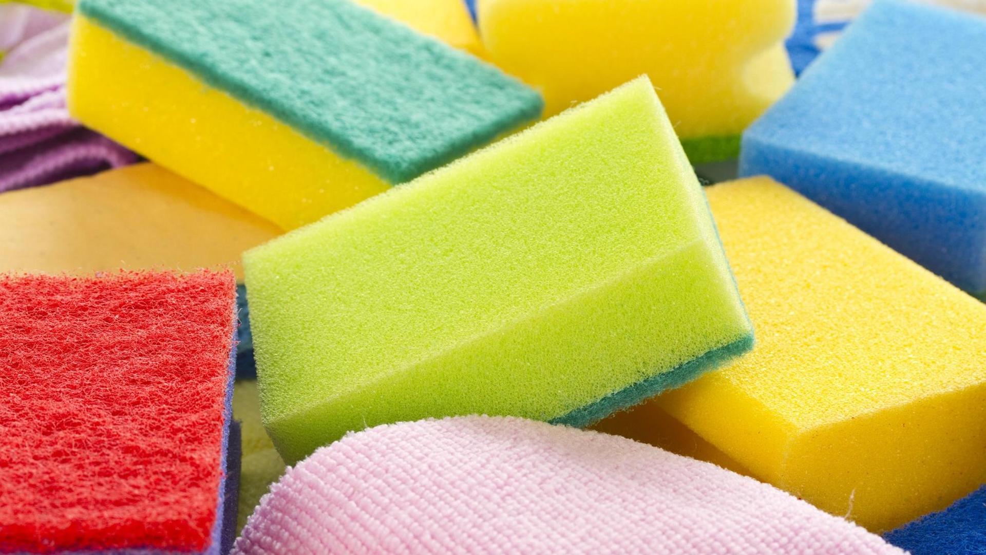 Mehrere Küchenschwämme liegen in verschiedenen Farben übereinander Mehrere Küchenschwämme liegen in verschiedenen Farben übereinander