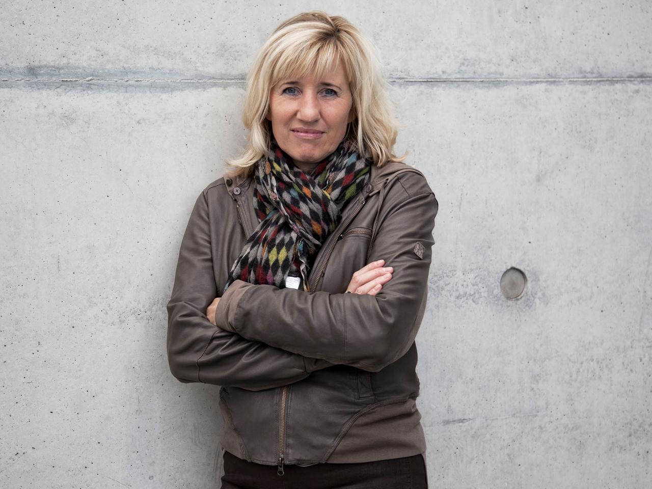 Die Schriftstellerin und Doping-Expertin Ines Geipel, die Arme verschränkt, an eine graue Betonmauer gelehnt. Die Schriftstellerin und Doping-Expertin Ines Geipel, die Arme verschränkt, an eine graue Betonmauer gelehnt.