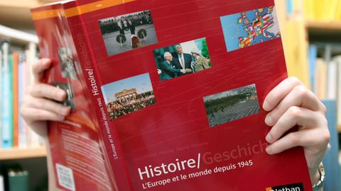 Eine Schülerin liest in einem Deutsch-französischen Geschichtsbuch