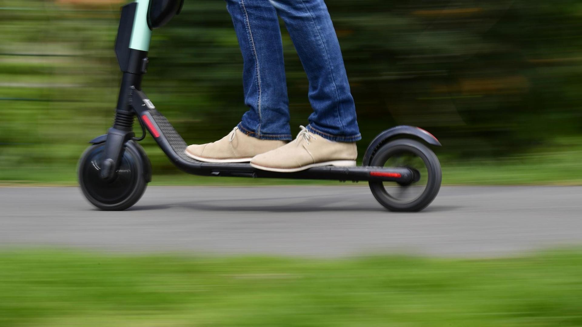 Die Füße eines Mannes auf einem E-Scooter. Die Füße eines Mannes auf einem E-Scooter.