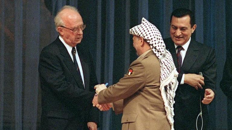 PLO-Chef Jassir Arafat und Israels Ministerpräsident Jitzchak Rabin reichen sich nach der Unterzeichnung des Gaza-Jericho-Abkommens am 4. Mai 1994