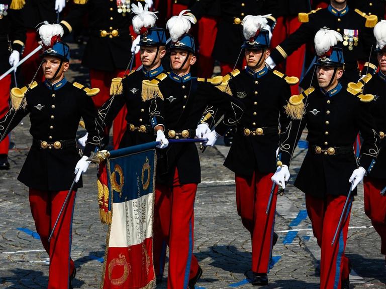 Soldaten in bunten Uniformen defilieren am 14. Juli über die Champs-Élysées in Paris.