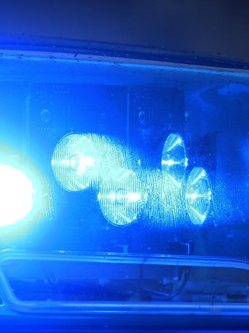 Blaulicht eines Polizeiautos, das von einer Pkw-Fensterscheibe reflektiert wird