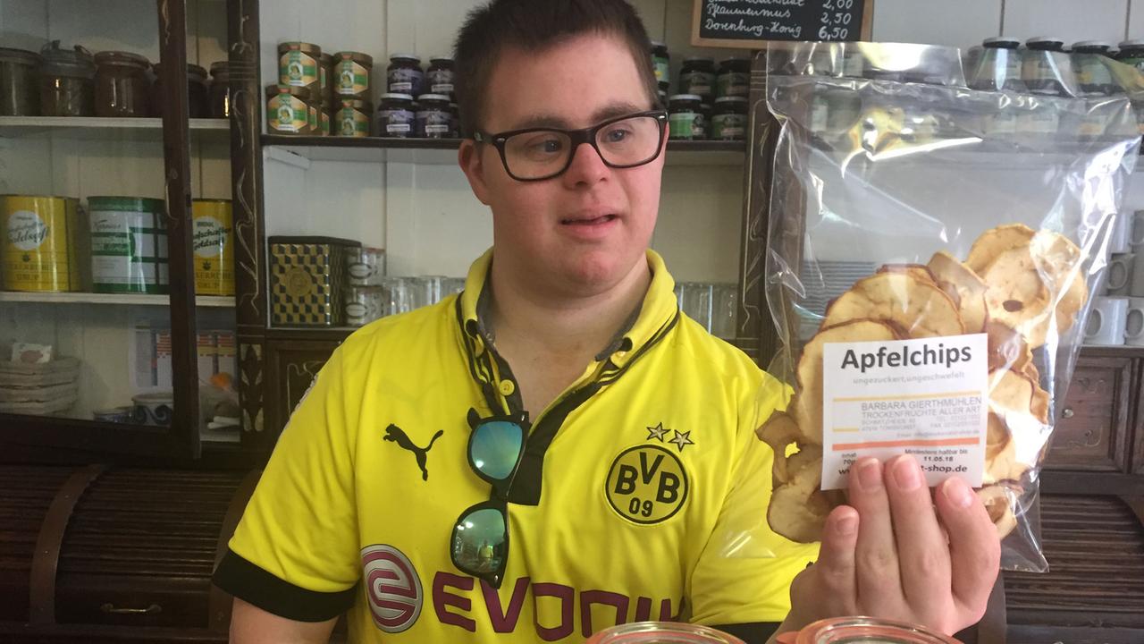 Julian Peters, 29 Jahre alt, gelbes Trikot von Borussia Dortmund mit Nuri Şahins Namen auf dem Rücken, führt durch den Tante-Emma-Laden der Elterninitative "Kindertraum Menschenleben", in dem er seit ein paar Wochen arbeitet.