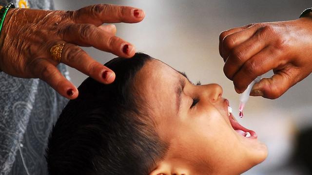 Ein Junge erhält die Kinderlähmung-Schluckimpfung und sperrt den Mund auf.