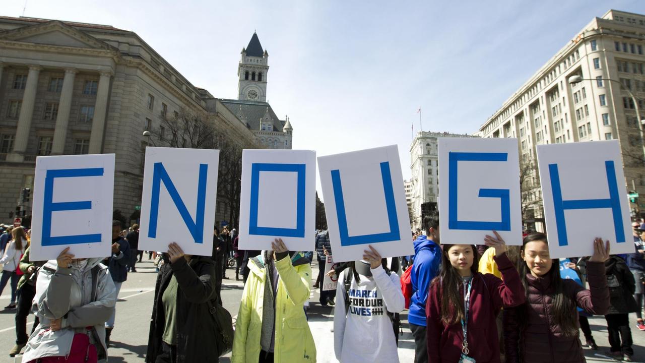 Demonstranen nehmen in Washington am "Marsch für unsere Leben" teil, sie halten Schilder hoch, auf denen die Groß´buchstaben "ENOUGH" stehen, "genug". Demonstranen nehmen in Washington am "Marsch für unsere Leben" teil, sie halten Schilder hoch, auf denen die Groß´buchstaben "ENOUGH" stehen, "genug".