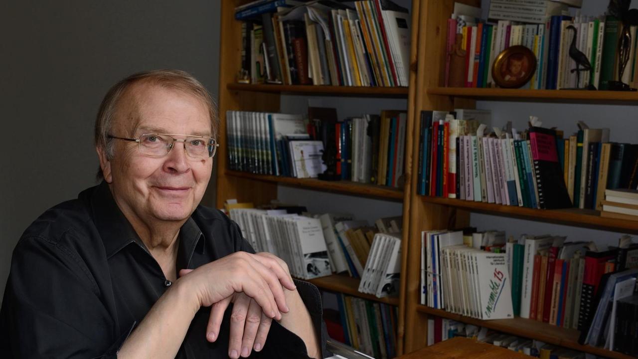 Wilhelm Genazino vor einem Bücherregal am Schreibtisch sitzend. Wilhelm Genazino vor einem Bücherregal am Schreibtisch sitzend.