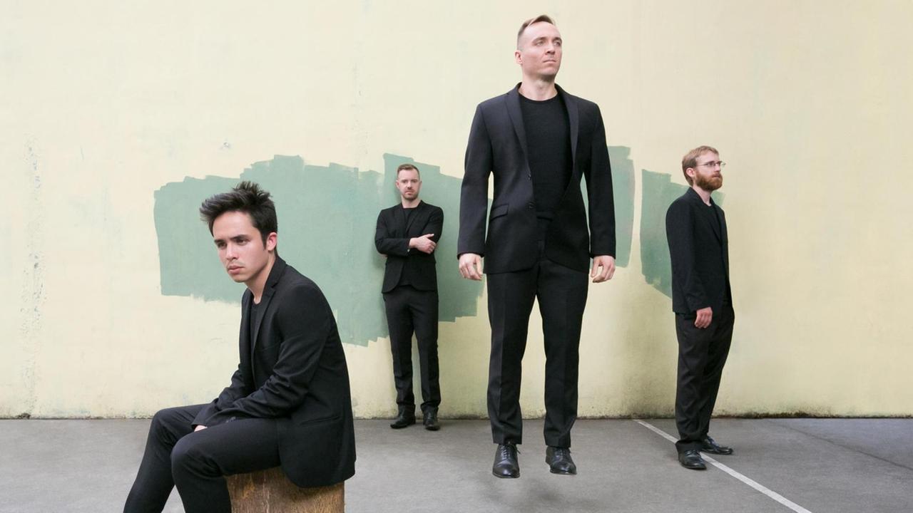 Einer der vier Musiker springt in die Höhe. Einer der vier Musiker springt in die Höhe.