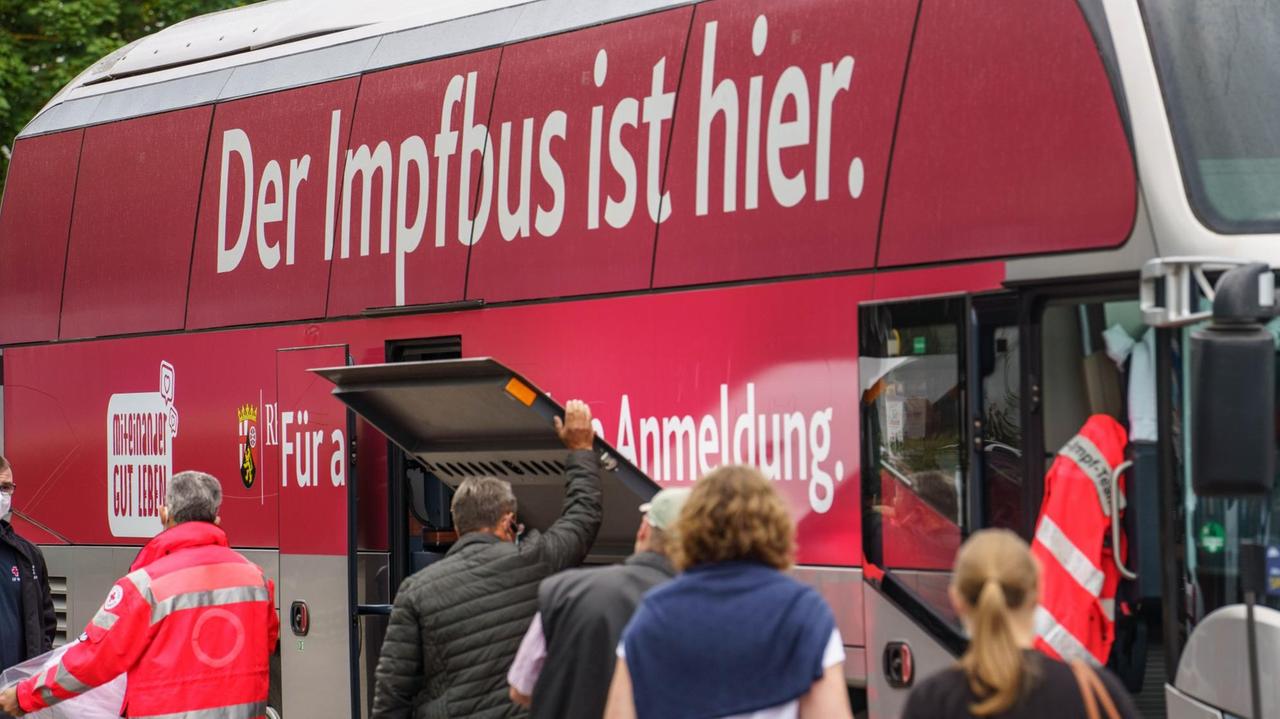 Menschen warten in einer Schlange ohne vorherige Anmeldung auf ihre Corona-Impfung vor einem Impfbus. Menschen warten in einer Schlange ohne vorherige Anmeldung auf ihre Corona-Impfung vor einem Impfbus.