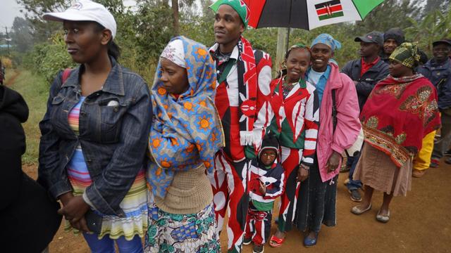 Der dreijährige Joseph Njoroge Kimani wartet mit seinem Vater James Kimani Njoroge und seiner Mutter Esther Wanjiru Njoroge, die Anzüge in den kenianischen Farben tragen, am 08.08.2017 in Gatundu (Kenia) vor einem Wahllokal auf die Stimmabgabe seiner Eltern.