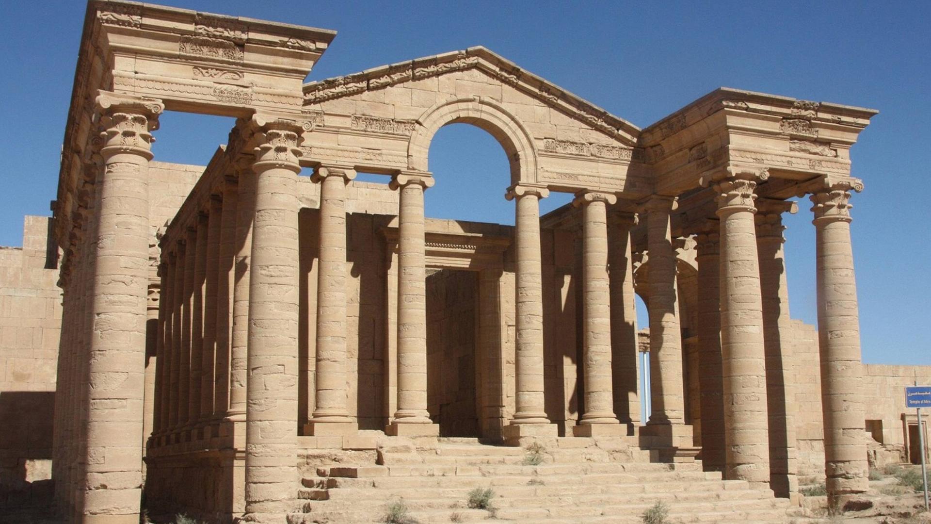 Ein antiker Tempel mit zwei Seitenflügeln und einer Treppe ohne Dach steht in der Wüste. Ein antiker Tempel mit zwei Seitenflügeln und einer Treppe ohne Dach steht in der Wüste.
