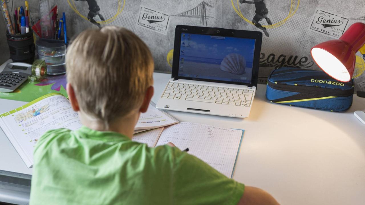 Ein Junge sitzt an seinem Schreibtisch und erledigt seine Mathe-Aufgaben im Homeschooling.