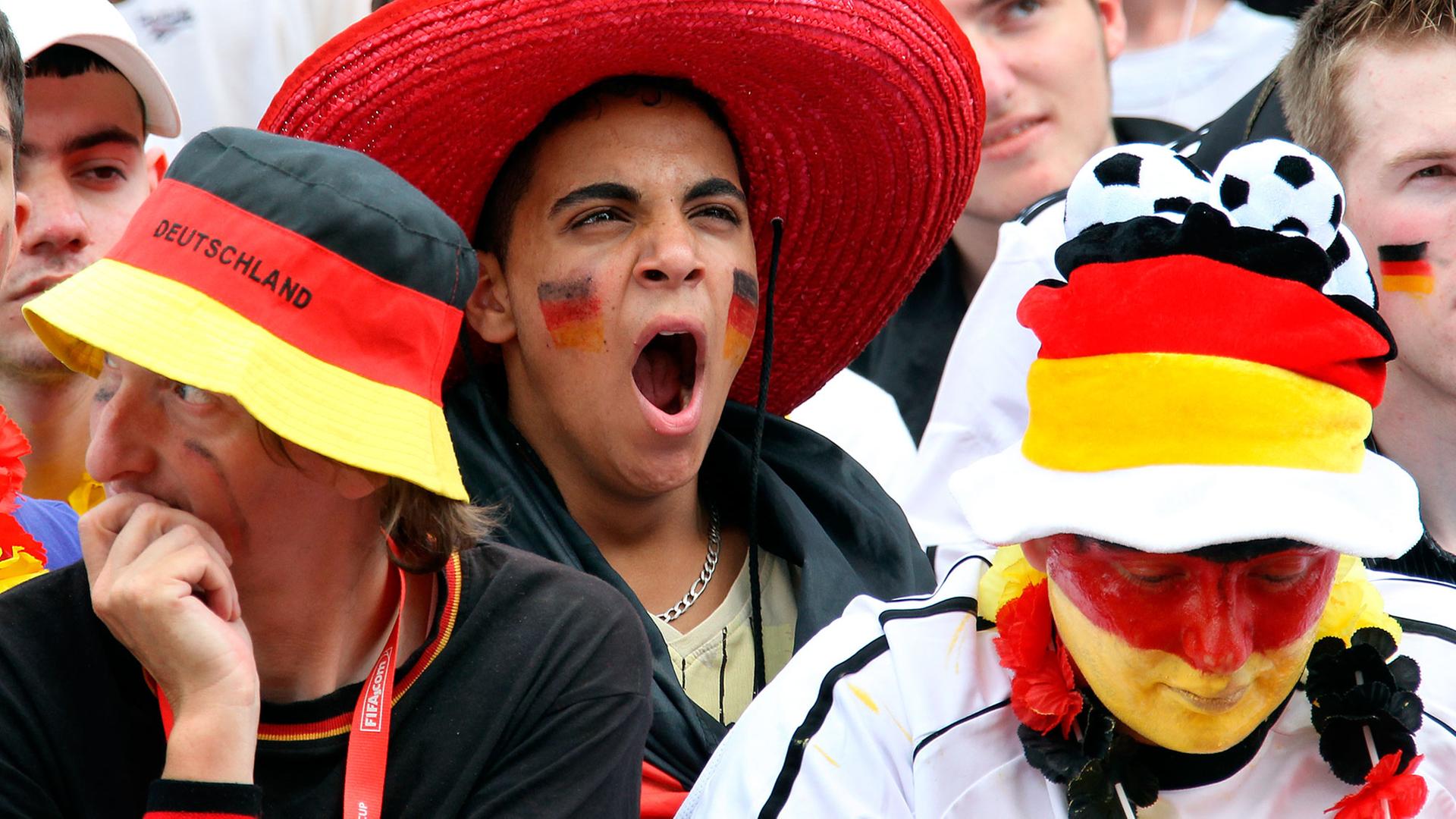 Sichtlich gelangweilt verfolgen Fußballfans am Freitag (18.06.2010) auf der Fanmeile vor dem Olympiastadion in Berlin die Niederlage der deutschen Elf bei derFußball-WM in Südafrika. Sichtlich gelangweilt verfolgen Fußballfans am Freitag (18.06.2010) auf der Fanmeile vor dem Olympiastadion in Berlin die Niederlage der deutschen Elf bei derFußball-WM in Südafrika.