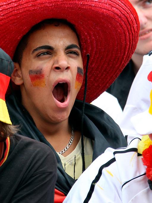 Sichtlich gelangweilt verfolgen Fußballfans am Freitag (18.06.2010) auf der Fanmeile vor dem Olympiastadion in Berlin die Niederlage der deutschen Elf bei derFußball-WM in Südafrika.