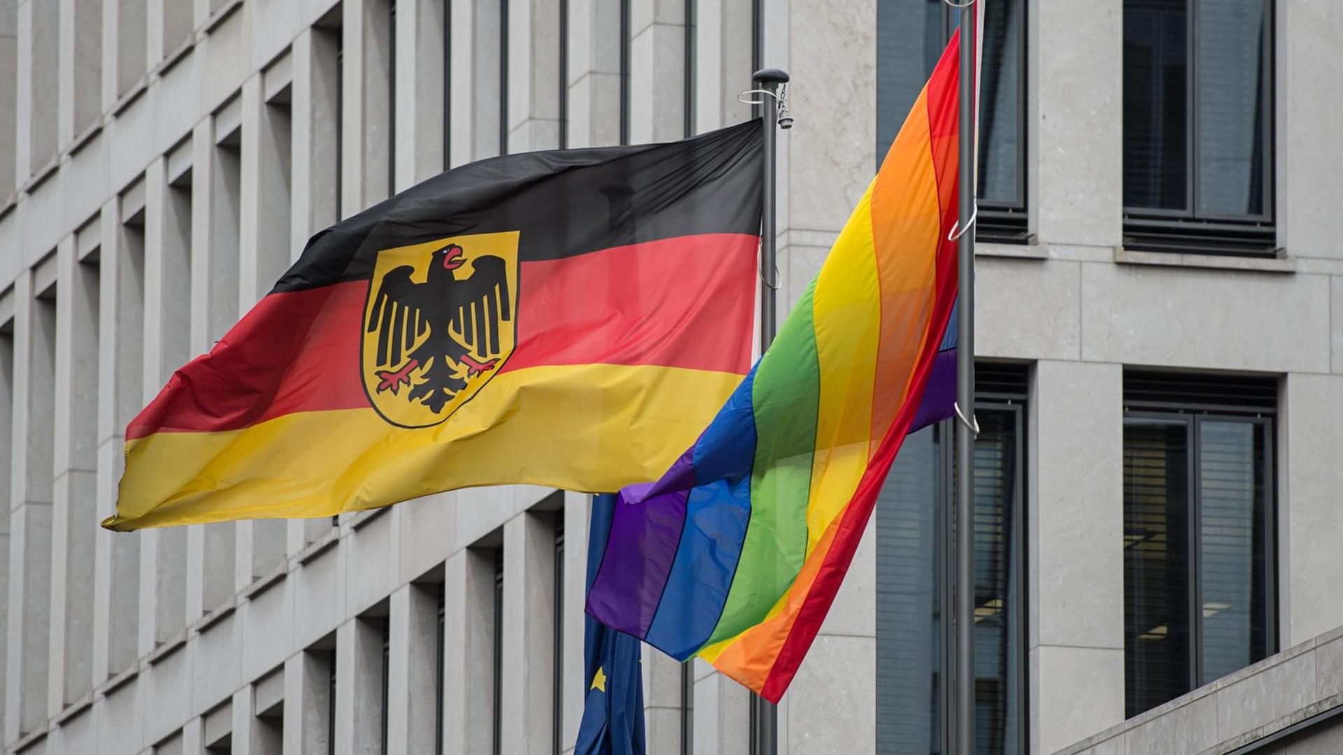 Eine Regenbogenflagge hängt am 12.07.2016 vor dem Familienministerium in Berlin neben der Bundesflagge. Die Flagge wird anlässlich der Pride-Week zum Christopher Street Day (CSD) - Berlin 2016 aufgezogen.