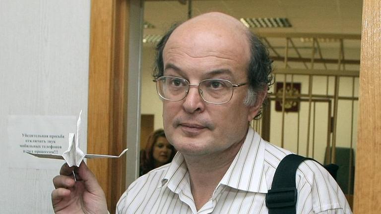 Man sieht den früheren Museumsdirektor Juri Samodurow mit einem Papierflugzeug in der Hand. Man sieht den früheren Museumsdirektor Juri Samodurow mit einem Papierflugzeug in der Hand.