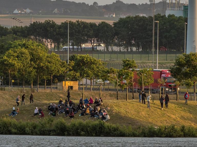 Flüchtlinge sitzen in der Nähe der Autobahn A16 bei Calais und warten auf ihre Chance, über den Eurotunnel nach Großbritannien zu gelangen.