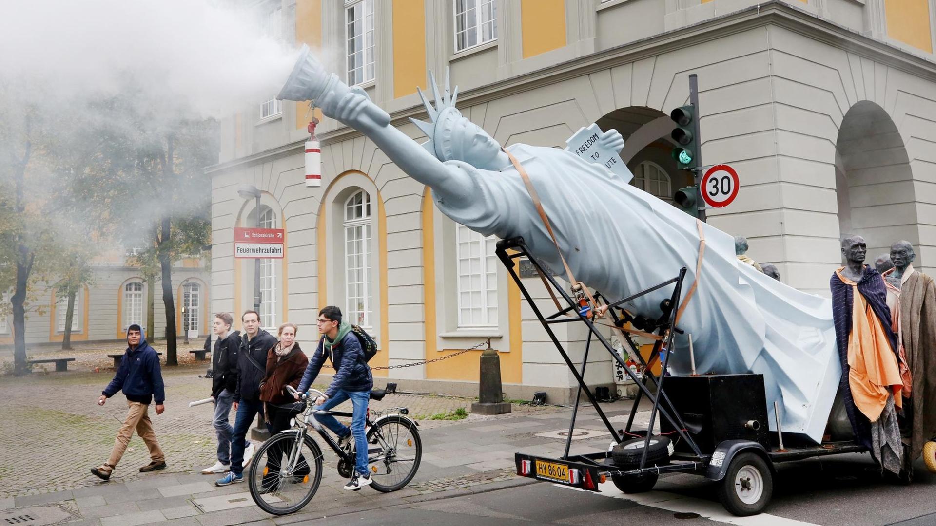 Mit einer qualmenden Freiheitsstatue ziehen Demonstranten am 04.11.2017 in Bonn (Nordrhein-Westfalen) für die Umsetzung des Weltklimaabkommens durch die Innenstadt. Die Demonstration findet im Vorfeld der Weltklimakonferenz statt, die am 06.11.2017 in Bonn beginnt Mit einer qualmenden Freiheitsstatue ziehen Demonstranten am 04.11.2017 in Bonn (Nordrhein-Westfalen) für die Umsetzung des Weltklimaabkommens durch die Innenstadt. Die Demonstration findet im Vorfeld der Weltklimakonferenz statt, die am 06.11.2017 in Bonn beginnt